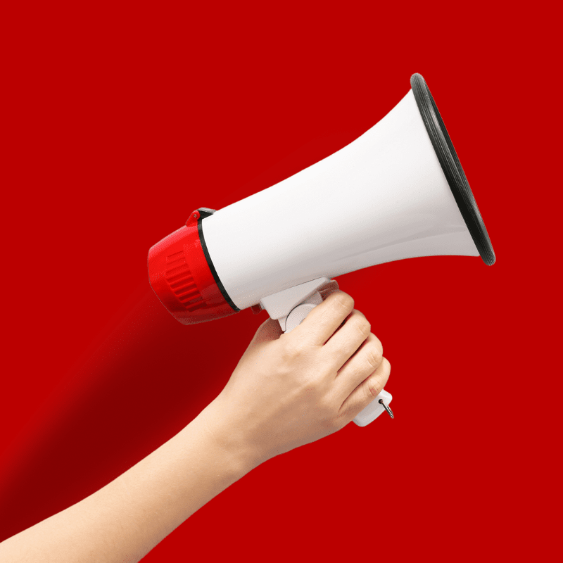 Megaphone on a red background being held by a woman's arm