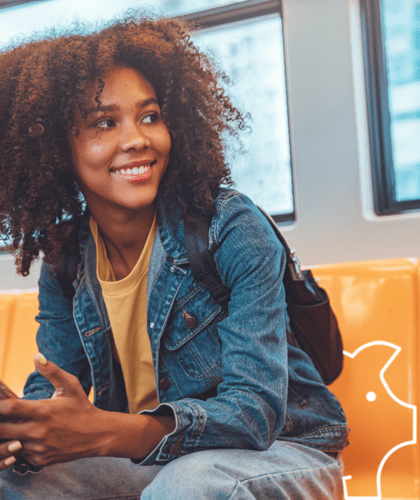 Woman of colour sitting on train looking at phone smiling